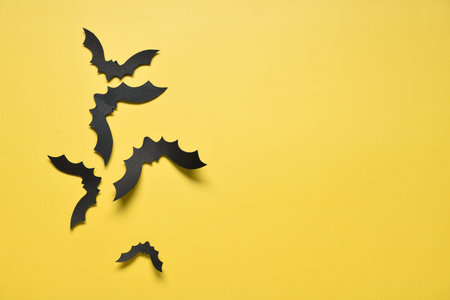 Paper bats for Halloween party on yellow background