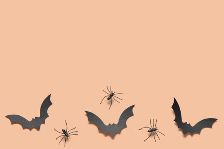 Paper bats and spiders for Halloween party on orange background