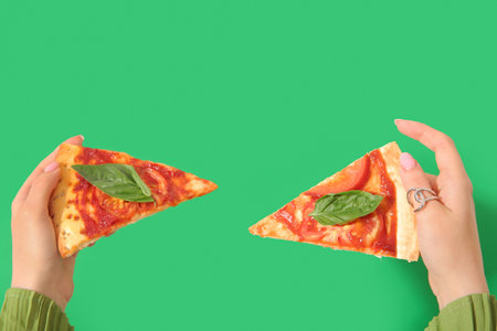 Woman holding slices of tasty pizza on green backgroundの写真素材