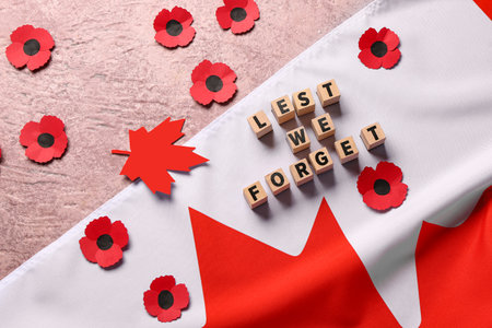 Poppy flowers with flag of Canada and text LEST WE FORGET on grunge pink background. Remembrance Dayの写真素材