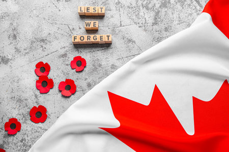 Poppy flowers with flag of Canada and text LEST WE FORGET on grunge gray background. Remembrance Dayの写真素材