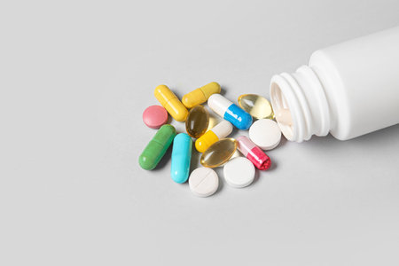Jar with different scattered pills on gray backgroundの写真素材
