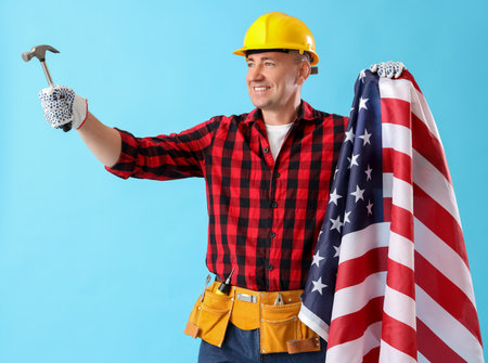 Mature worker with hammer and USA flag on blue background. labor day celebrationの写真素材