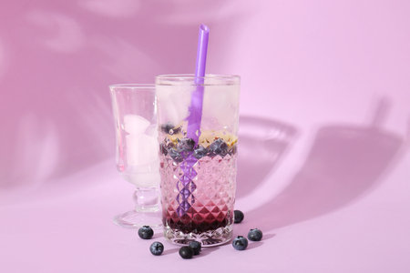 Glass of fresh blueberry lemonade on lilac backgroundの写真素材
