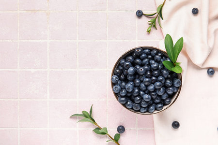 Bowl with fresh blueberries and leaves on pink tile backgroundの写真素材