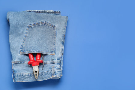 Jeans with pliers in pocket on blue background. labor day celebrationの写真素材