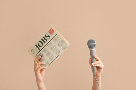 Female hands with microphone and newspaper on color backgroundの写真素材