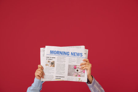 Female hands with newspapers against color backgroundの写真素材