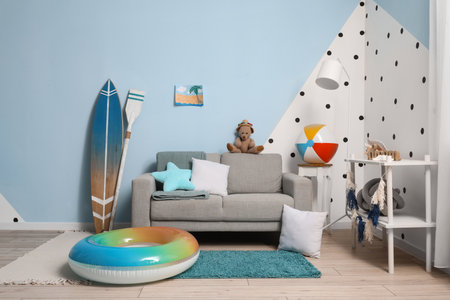 Interior of children's room with gray sofa, surfing board and beach accessoriesの写真素材