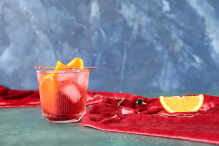 Glass of cold Negroni cocktail and female accessories on color backgroundの写真素材