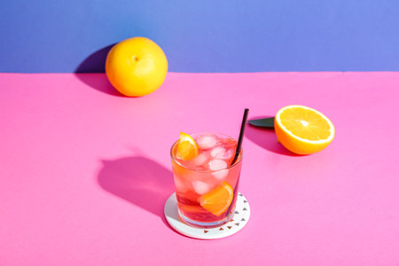 Glass of delicious Negroni cocktail and oranges on color background