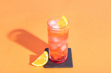 Glass of delicious Negroni cocktail with ice cubes and orange on color backgroundの写真素材