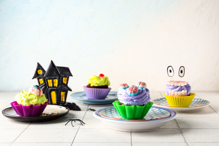 Composition with delicious Halloween cupcakes and paper house on light backgroundの写真素材