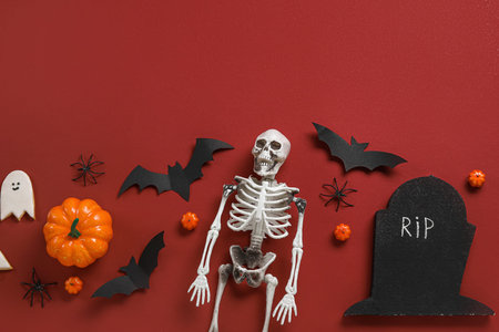Composition with skeleton and Halloween decor on red background