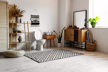 Interior of modern restroom with ceramic toilet bowl, wooden vanity cabinet and shelving unitの写真素材