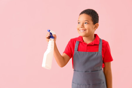 Cute African-American boy with detergent bottle on pink backgroundの写真素材