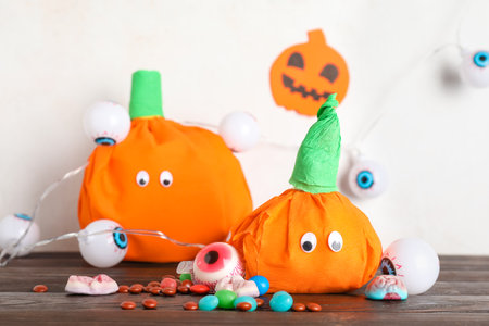 Paper pumpkins for Halloween and tasty candies on dark wooden table, closeupの写真素材