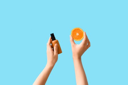 Woman with cosmetic product and orange on blue backgroundの写真素材