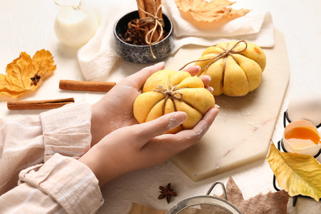 Woman preparing pumpkin shaped buns on white backgroundの写真素材