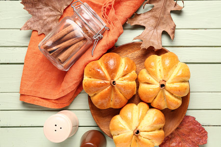 Plate with tasty pumpkin shaped buns on green wooden background