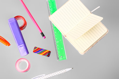 Flying blank notebook with different stationery on gray backgroundの写真素材