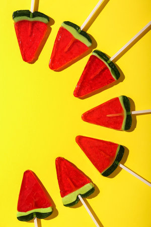 Lollipops in shape of watermelon slice on yellow backgroundの写真素材