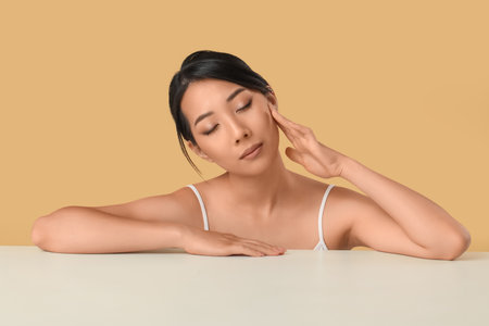 Beautiful young Asian woman with healthy skin on beige backgroundの写真素材