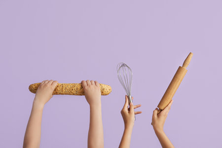 Female hands with baguette, whisk and rolling pin on lilac backgroundの写真素材