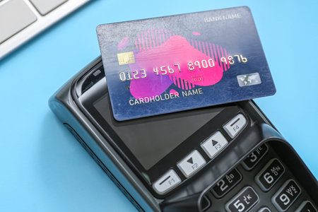 Payment terminal and credit card on blue background