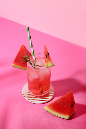 Glass of tasty watermelon cocktail on pink table near wallの写真素材