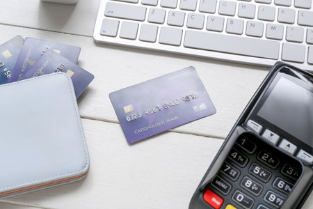 Keyboard with payment terminal, wallet and credit cards on white wooden backgroundの写真素材