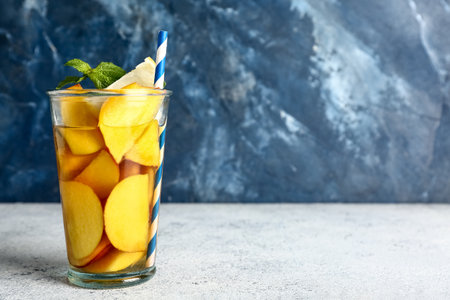 Glass of fresh peach lemonade with mint on white tableの写真素材