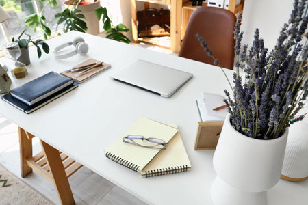 Laptop with stationery on desk in officeの写真素材