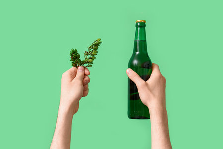 Man with bottle of beer and hop on green backgroundの写真素材