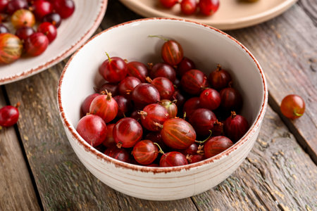 Bowl with fresh gooseberries on gray wooden backgroundの写真素材