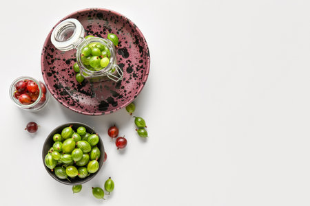 Bowl and jars with fresh gooseberries on white backgroundの写真素材