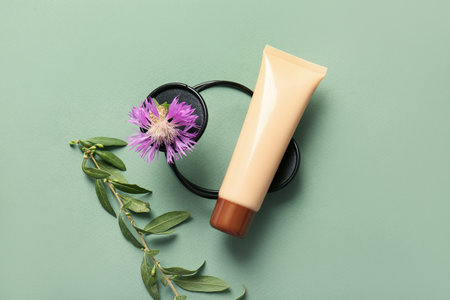 Composition with tube of cosmetic product, flower and plant branch on color backgroundの写真素材