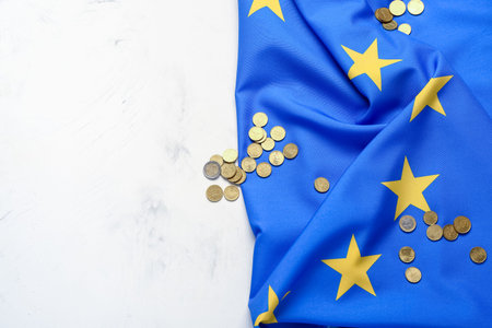 Coins and European Union flag on light backgroundの写真素材