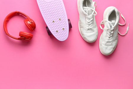 Pair of sneakers, skateboard and headphones on pink backgroundの写真素材
