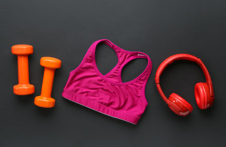 Dumbbells, sports bra and headphones on dark backgroundの写真素材