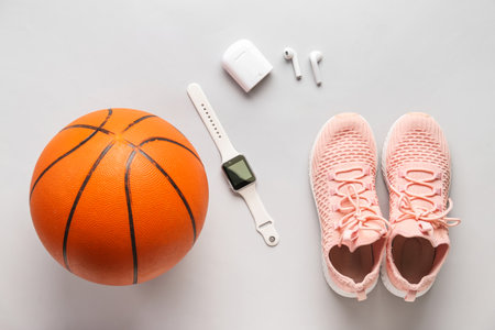 Pair of sneakers, ball for playing basketball and modern gadgets on light backgroundの写真素材