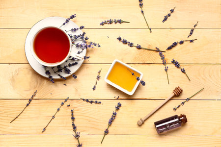 Bowl with sweet lavender honey and cup of tea on wooden backgroundの写真素材