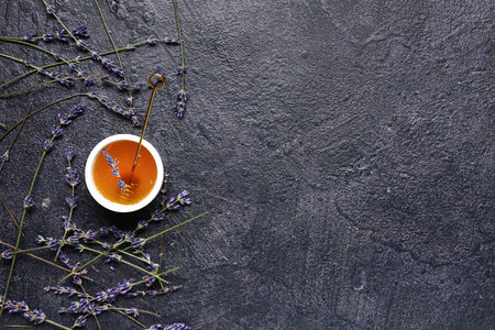 Bowl of sweet lavender honey, dipper and flowers on dark backgroundの写真素材