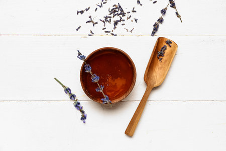 Bowl of sweet lavender honey and flowers on white wooden backgroundの写真素材