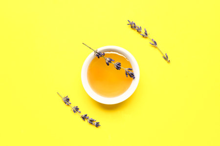 Bowl of sweet lavender honey and flowers on yellow backgroundの写真素材