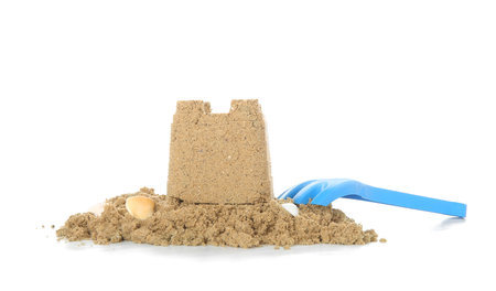 Castle made of sand with toy rake isolated on white backgroundの写真素材