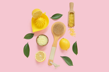 Bowl of lemon body scrub with juicer, sea salt and massage brush on pink backgroundの写真素材