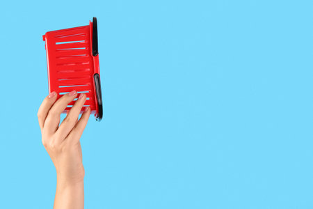 Woman holding mini shopping basket on blue backgroundの写真素材