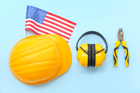Hardhat, earmuffs, pliers and USA flag on blue background. labor day celebrationの写真素材