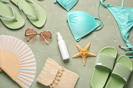 Bottle of sunscreen cream with beach accessories on grunge green backgroundの写真素材